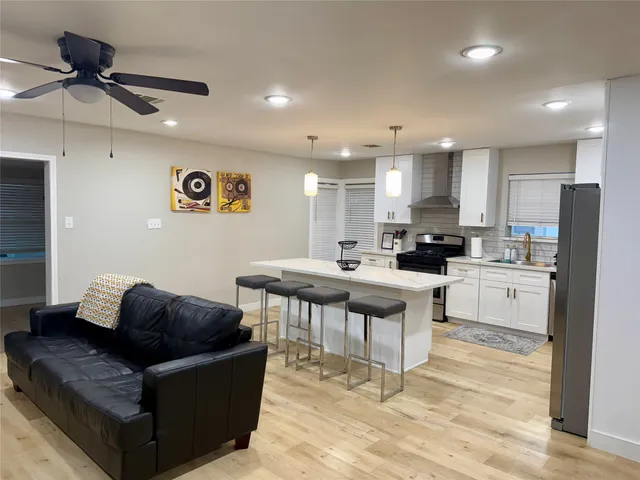 a living room with stainless steel appliances kitchen island granite countertop a couch and a view of kitchen appliances