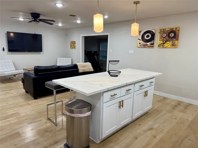 a kitchen with a stove a flat screen tv and wooden floor