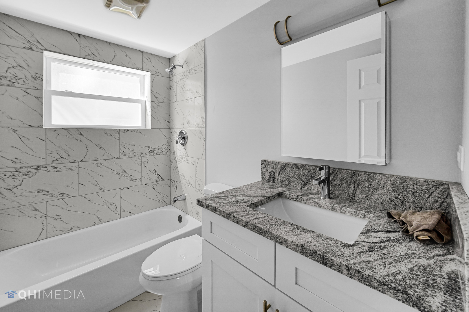 135 Custer Avenue, Unit 1 Evanston, IL 60202 - Photo 8 of 14 a bathroom with a granite countertop sink a toilet and bathtub