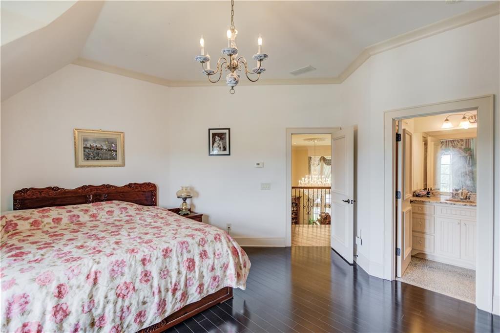 5004 Gunnison Trace Suwanee, GA 30024 - Photo 59 of 108 a bedroom with a large bed and a chandelier