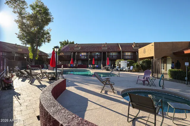 a view of a patio with couches table and chairs under an umbrella with a barbeque
