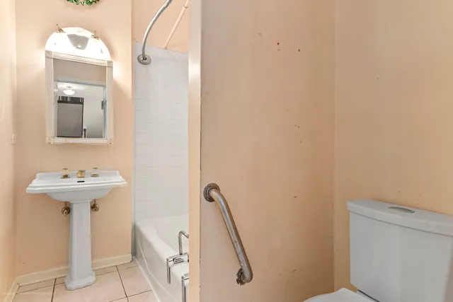 a view of a white house with a yard plants and large tree
