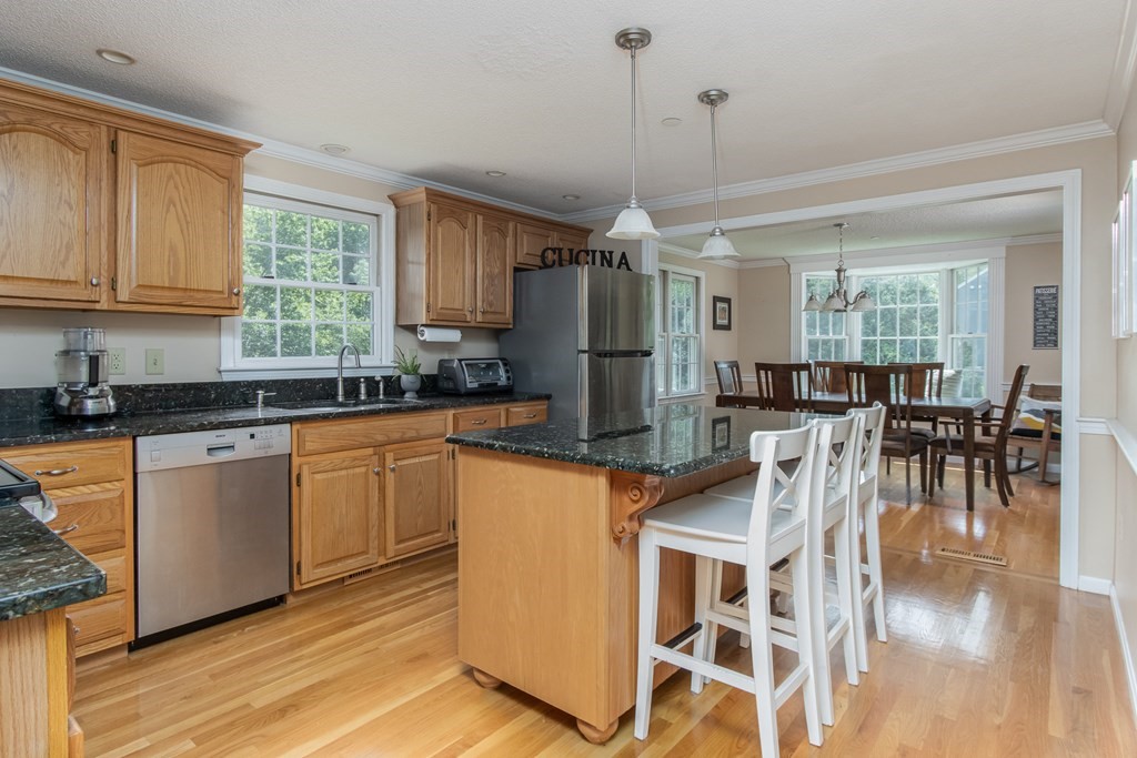 19 Hammond Farm Road Haverhill, MA 01832 - Photo 14 of 42 a kitchen with stainless steel appliances granite countertop a stove top oven a refrigerator a dining table and chairs with wooden floor