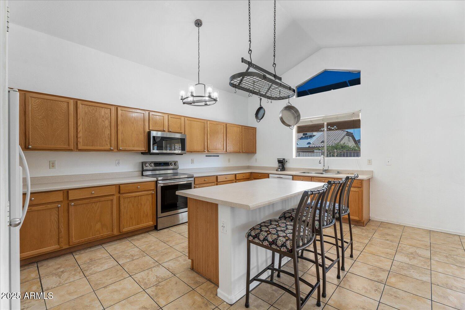12745 West Calavar Road El Mirage, AZ 85335 - Photo 15 of 56 a kitchen with stainless steel appliances granite countertop a sink dishwasher a stove a refrigerator with a dining table and chairs with wooden floor