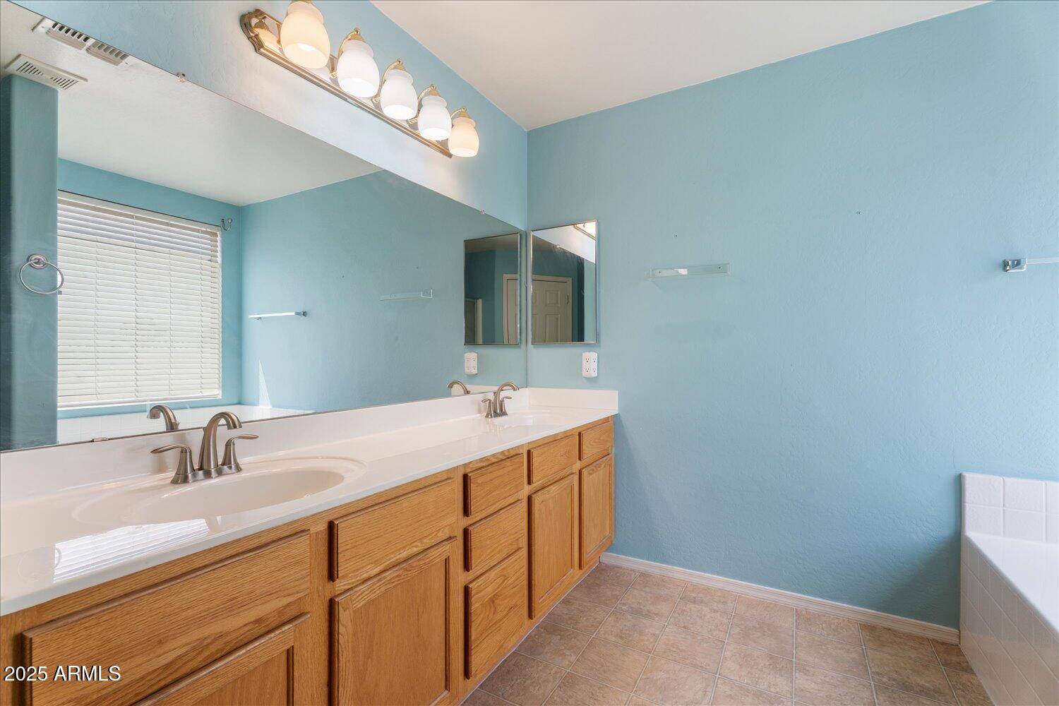 12745 West Calavar Road El Mirage, AZ 85335 - Photo 27 of 56 a bathroom with a double vanity sink and a mirror