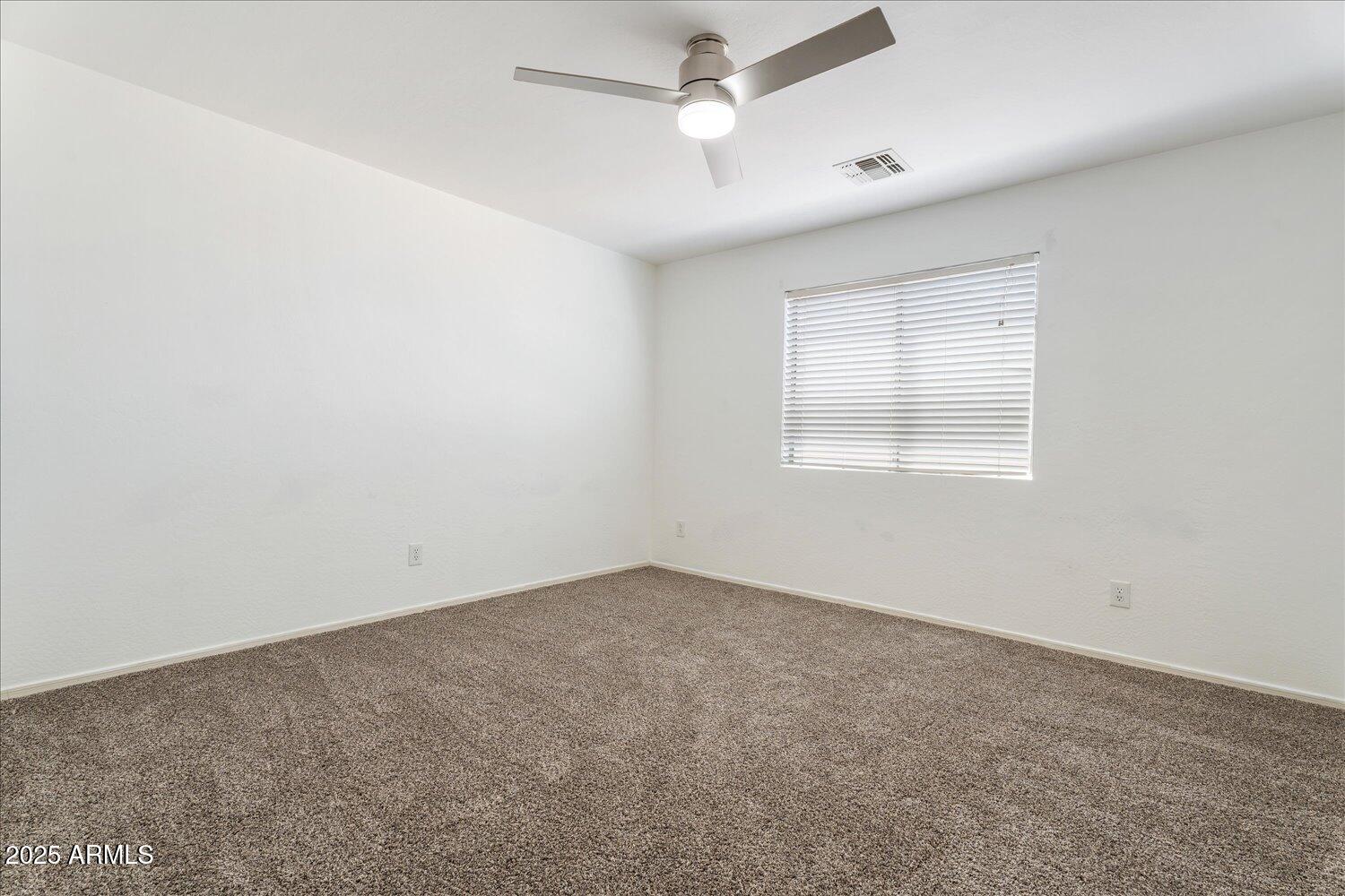 12745 West Calavar Road El Mirage, AZ 85335 - Photo 35 of 56 an empty room with a window and ceiling fan
