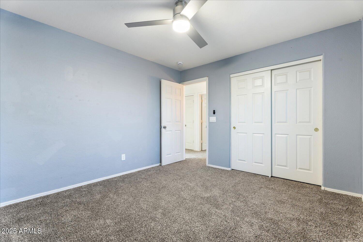 12745 West Calavar Road El Mirage, AZ 85335 - Photo 40 of 56 an empty room with closet and a ceiling fan