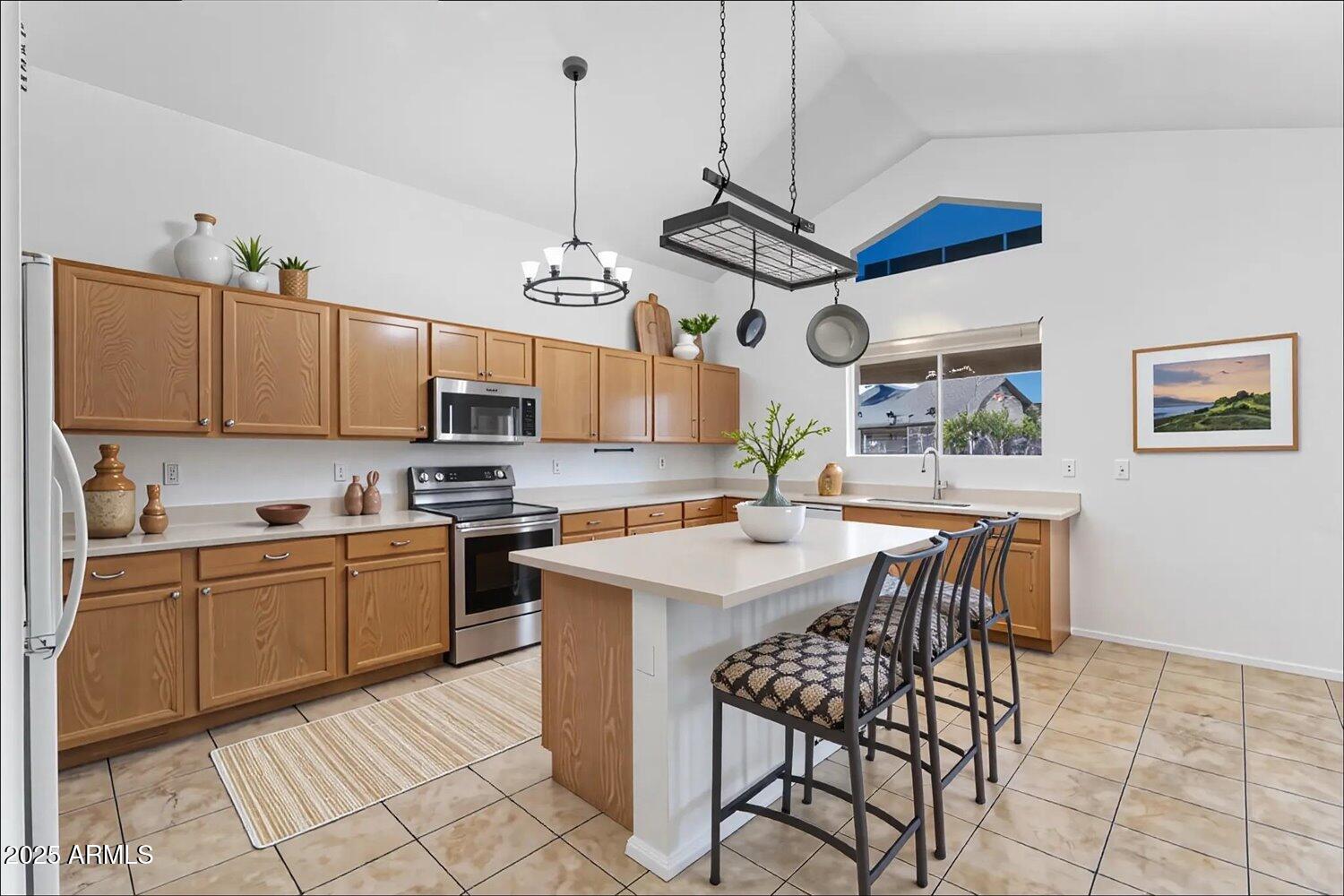 12745 West Calavar Road El Mirage, AZ 85335 - Photo 4 of 56 a kitchen with stainless steel appliances granite countertop a sink a stove a dining table and chairs with wooden floor
