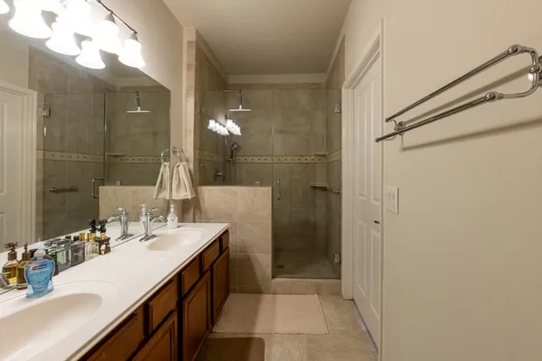 a bathroom with a double vanity sink mirror and shower