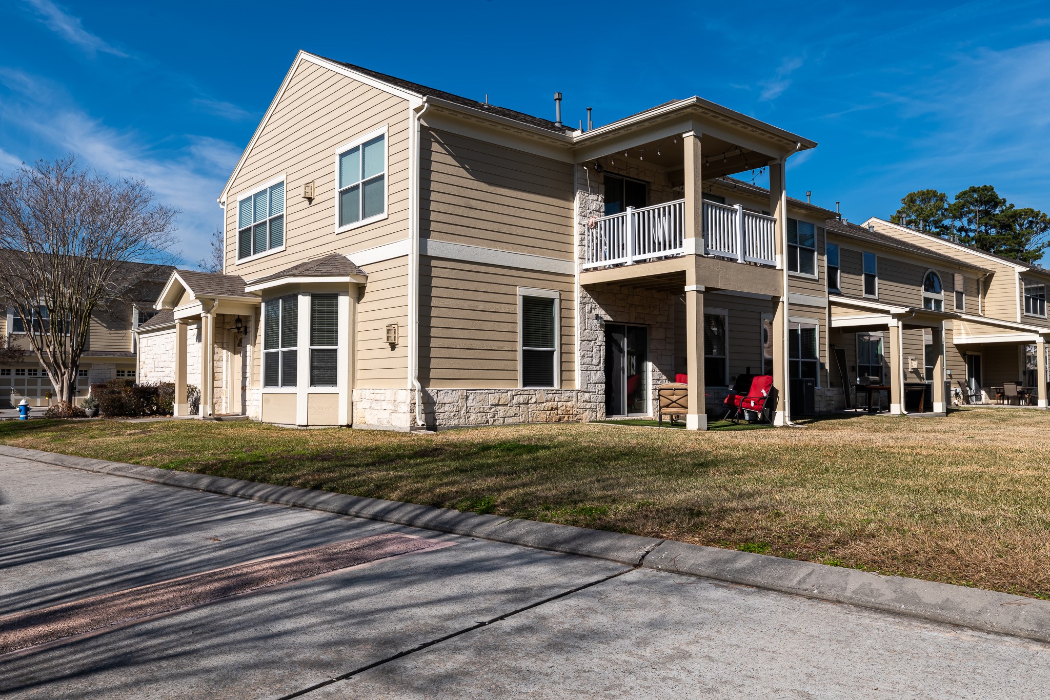13600 Breton Ridge Street, Unit 29F Houston, TX 77070 - Photo 19 of 21 This is a one-story condominium with a covered patio has a beige exterior, stone accents, and white trim. It features a well-maintained lawn and green space. The neighborhood appears peaceful and well-kept.