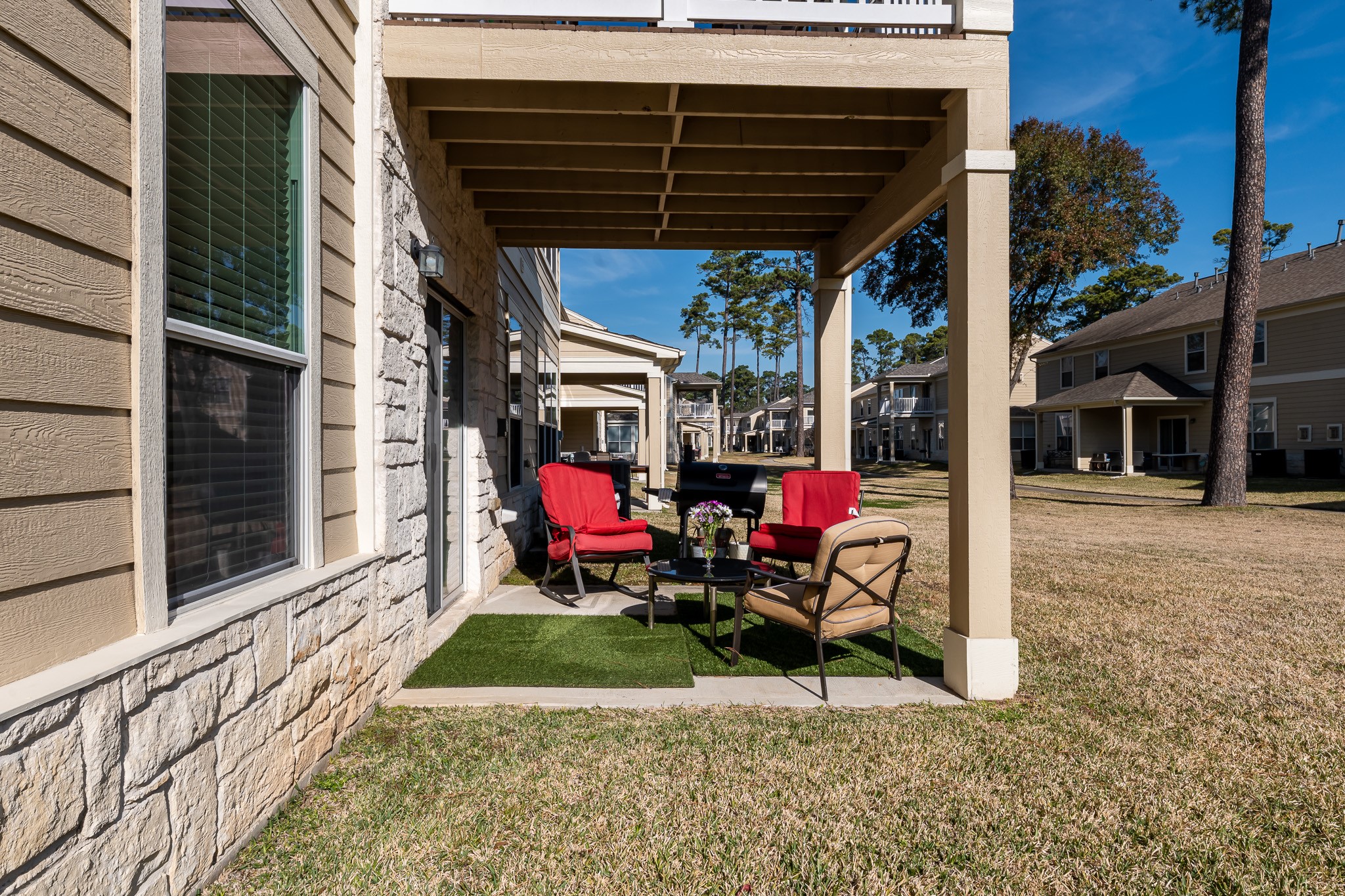 13600 Breton Ridge Street, Unit 29F Houston, TX 77070 - Photo 20 of 21 This photo showcases a cozy covered patio area which can provide comfortable seating. It is set against a backdrop of well-maintained grass and neighboring homes. Ideal for outdoor relaxation and entertaining.