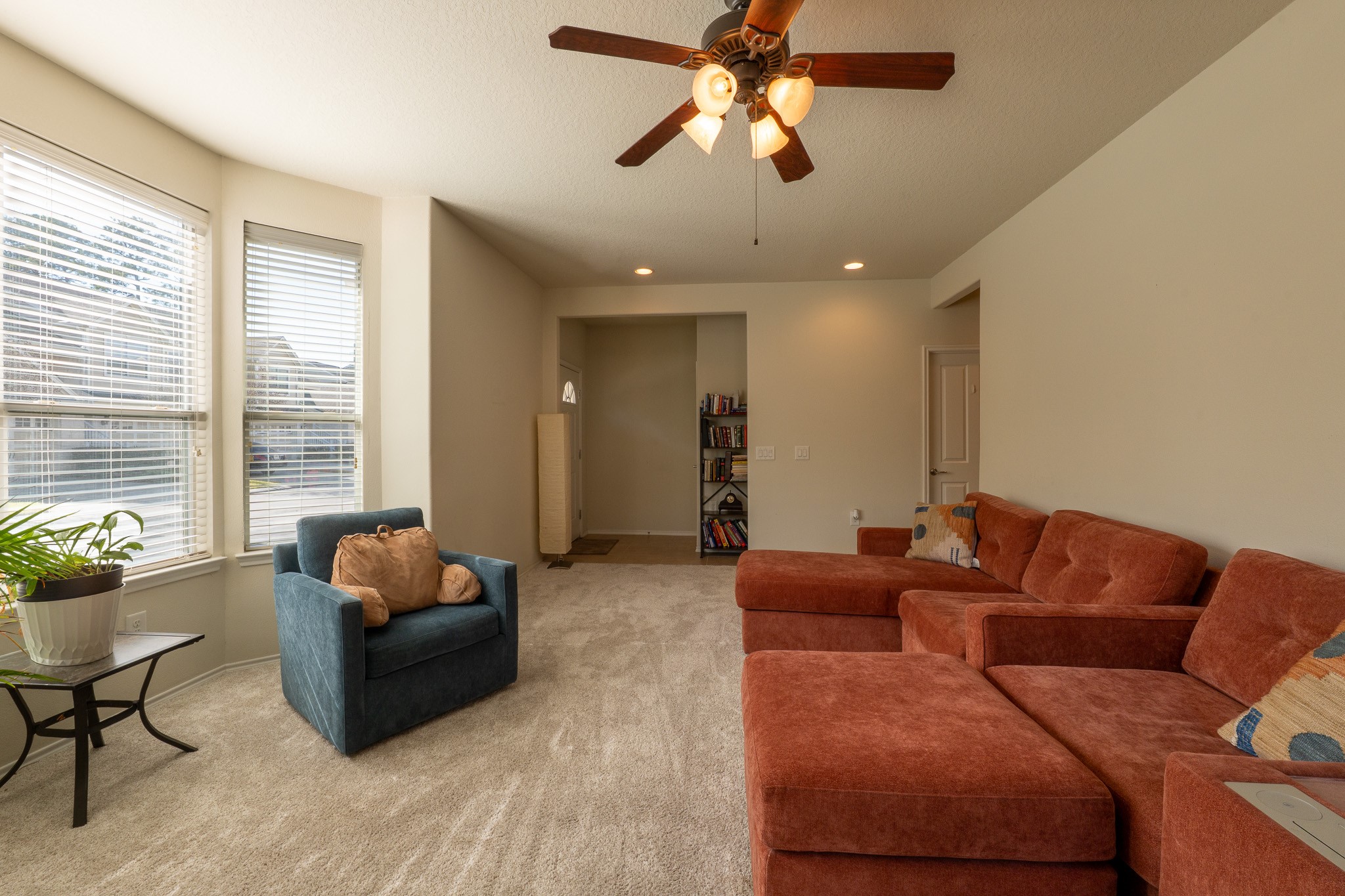 13600 Breton Ridge Street, Unit 29F Houston, TX 77070 - Photo 6 of 21 Bright living room with large windows, plush carpet, and cozy seating area. Features a ceiling fan and neutral walls, creating a spacious and inviting atmosphere.