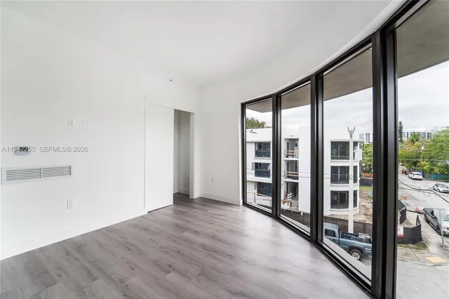 an empty room with wooden floor and windows