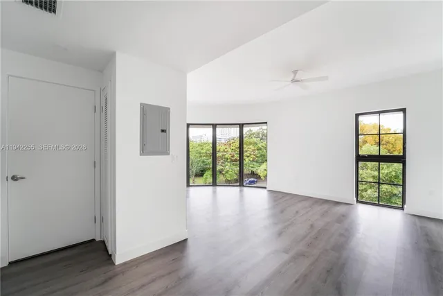 an empty room with wooden floor and windows