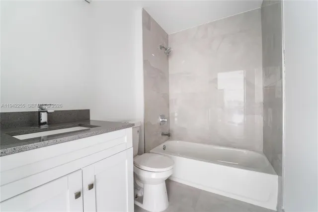 a bathroom with a granite countertop sink a toilet and bathtub