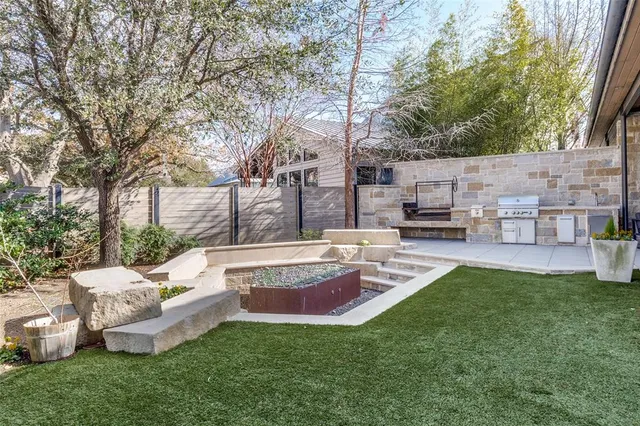 a view of a backyard with table and chairs potted plants and a large tree