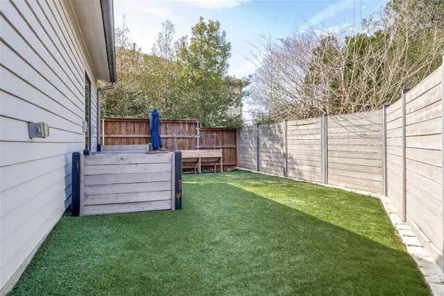 a view of a backyard with wooden fence and large trees