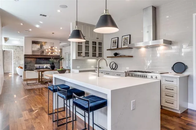 a kitchen with stainless steel appliances granite countertop a sink a stove and a wooden floors