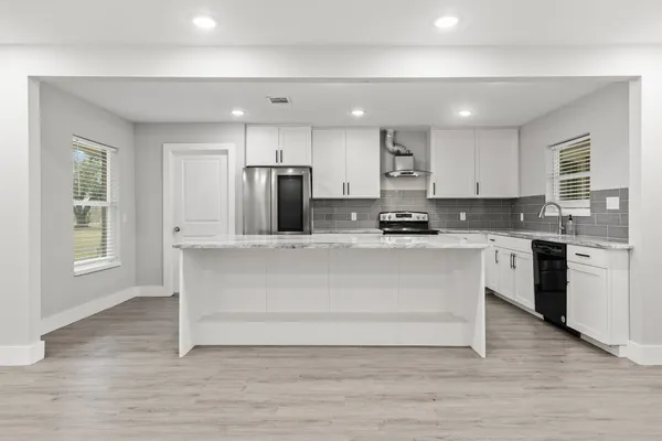 a kitchen with kitchen island white cabinets and stainless steel appliances