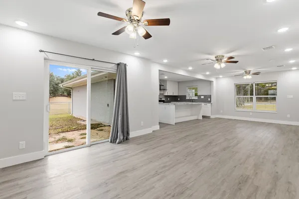 an empty room with wooden floor and a ceiling fan
