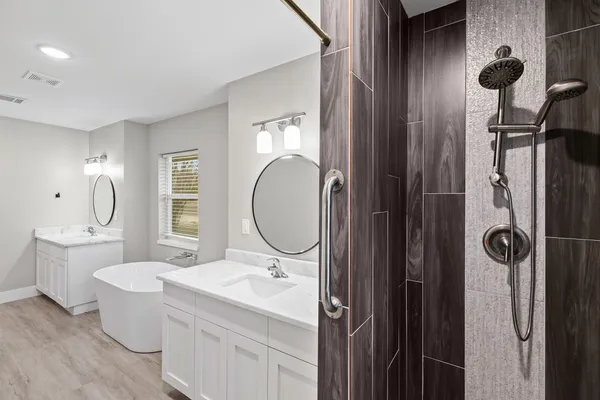 a bathroom with a double vanity sink a large mirror and bathtub