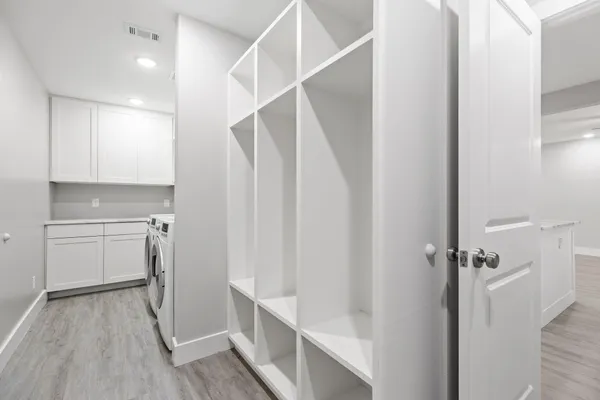 an empty room with wooden floor cabinet and windows