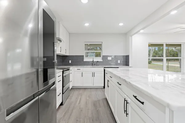 a large kitchen with granite countertop a large counter top space appliances and cabinets