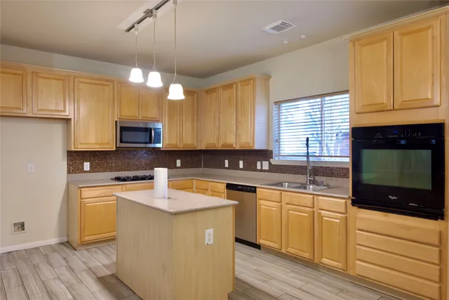 a kitchen with stainless steel appliances granite countertop a sink a stove cabinets and wooden floor