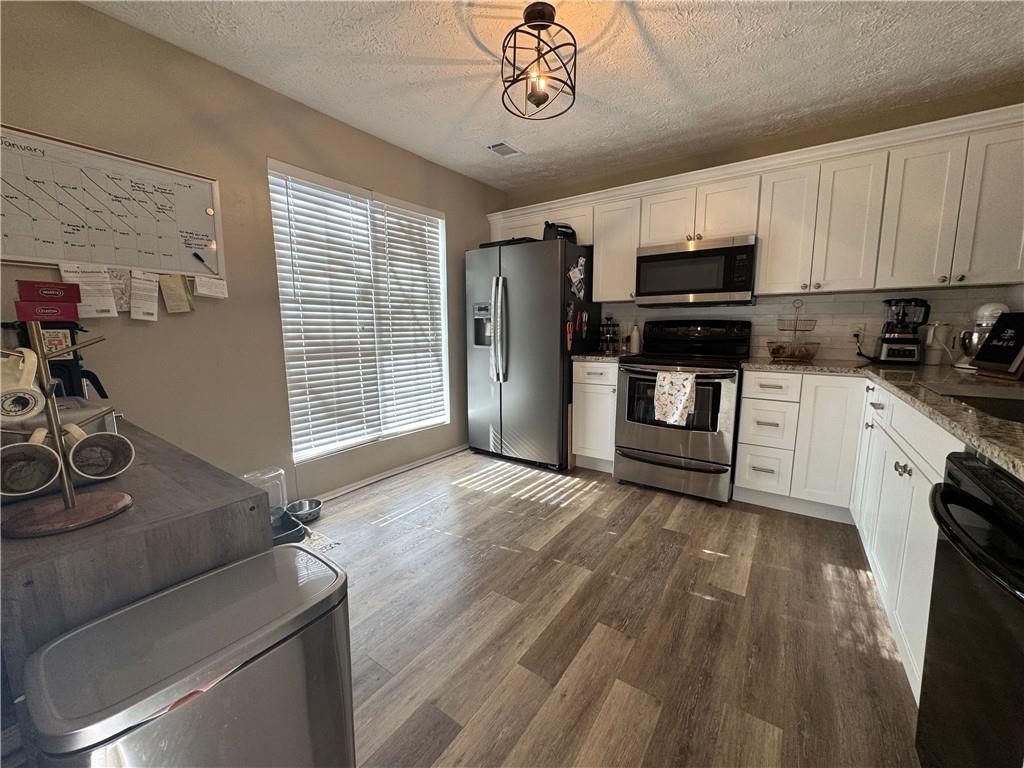 2104 Queen Anne Court Sandy Springs, GA 30350 - Photo 6 of 29 a kitchen with stainless steel appliances granite countertop a refrigerator oven a sink dishwasher and white cabinets with wooden floor