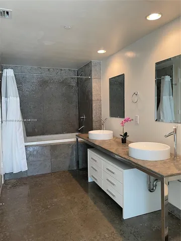 a bathroom with a granite countertop sink a mirror and a bathtub