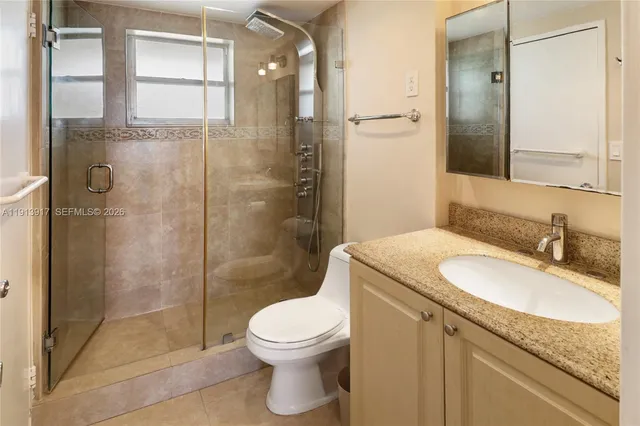 a bathroom with a granite countertop sink toilet and shower