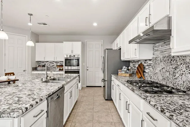 a kitchen with stainless steel appliances granite countertop a sink stove and cabinets