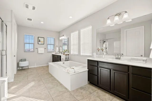 a spacious bathroom with a double vanity sink a mirror and a bathtub