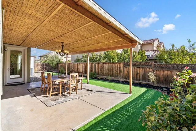 a view of a backyard with table and chairs under an umbrella with a small yard