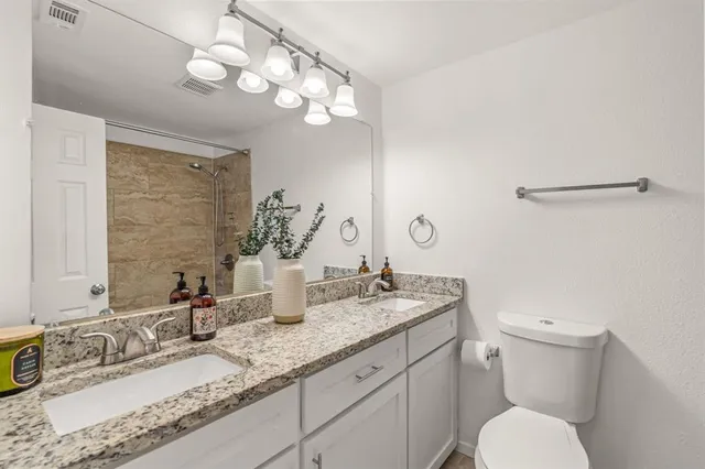 a bathroom with a granite countertop sink a toilet and a mirror