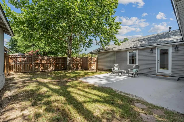 a view of a backyard with table and chairs and a large tree