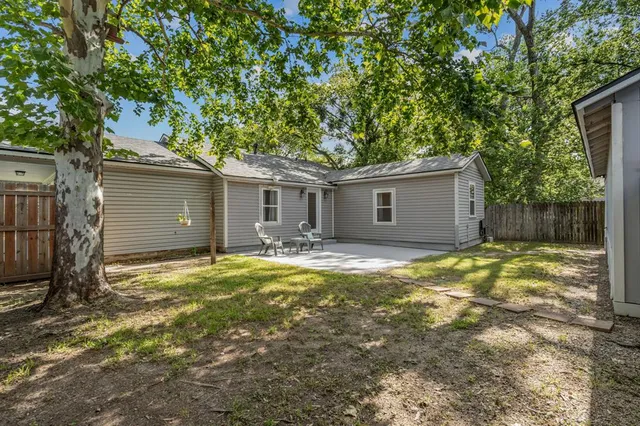 a view of a house with a yard and large tree