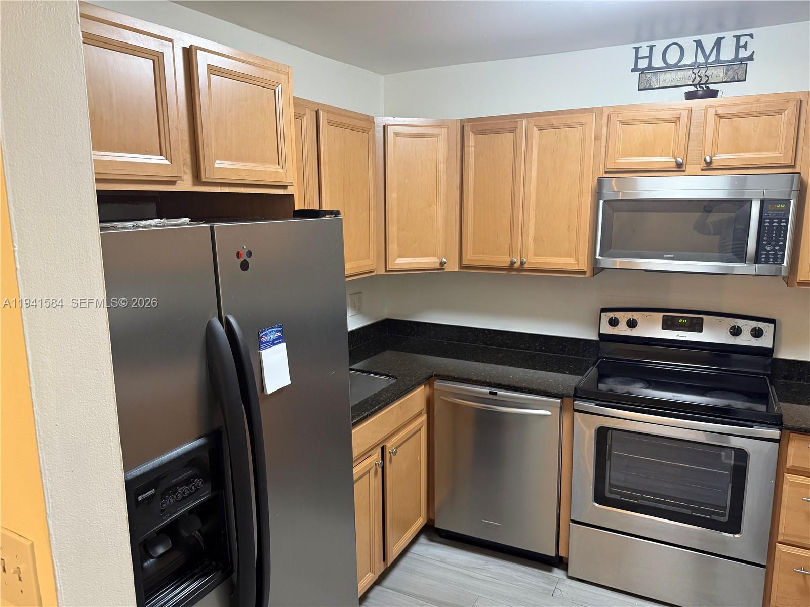 8620 Southwest 149th Avenue, Unit 416 Miami, FL 33193 - Photo 5 of 21 a kitchen with granite countertop a refrigerator stove and microwave