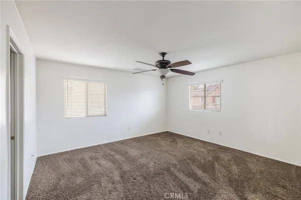 a view of a big room with a ceiling fan and windows