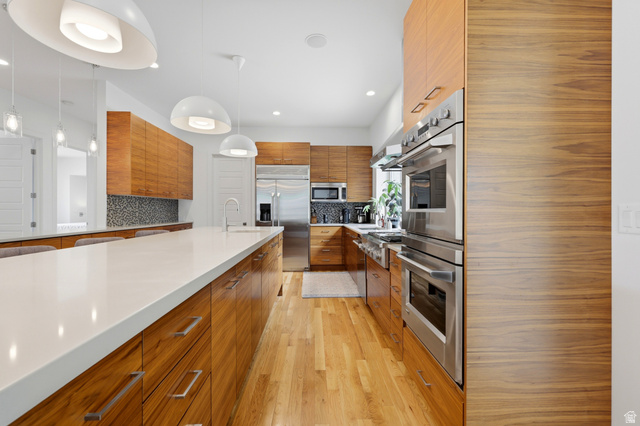 1389 Millbrook Way Bountiful, UT 84010 - Photo 28 of 74 Gourmet kitchen with extensive wood-finish cabinetry, a large central island featuring a white countertop, and stainless steel appliances including a built-in double oven and refrigerator