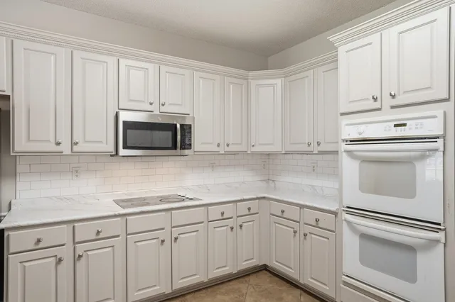 a kitchen with white cabinets and white appliances