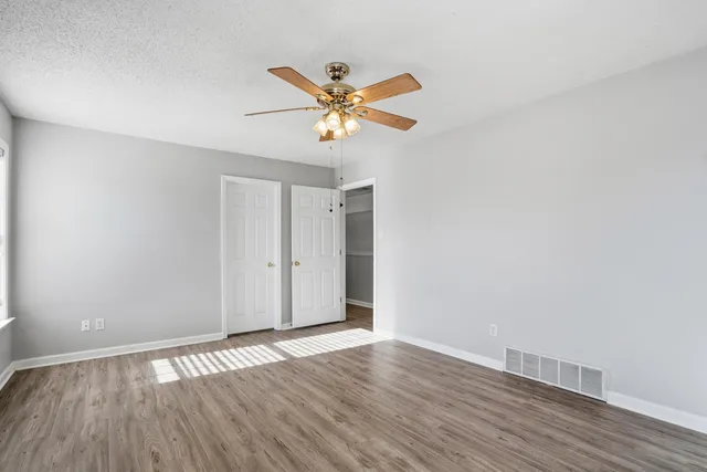 a view of a room with wooden floor and a ceiling fan