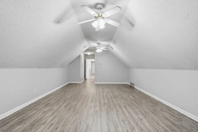 wooden floor in an empty room with a chandelier fan