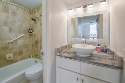 a bathroom with a granite countertop sink toilet shower and bathtub