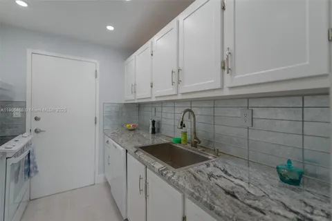 a kitchen with stainless steel appliances granite countertop a sink a stove white cabinets and a granite counter tops