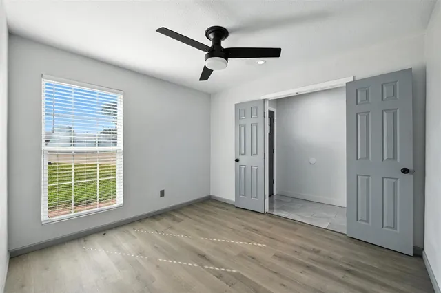 a view of empty room with wooden floor and fan