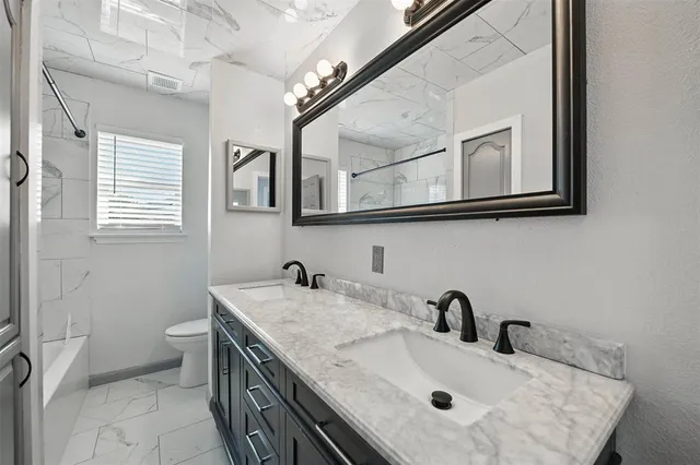 a bathroom with a granite countertop sink a toilet and a mirror