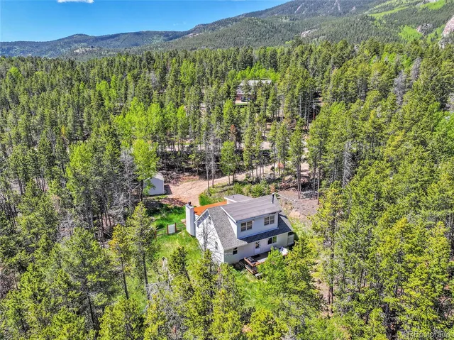 a view of a house with a yard and a large tree