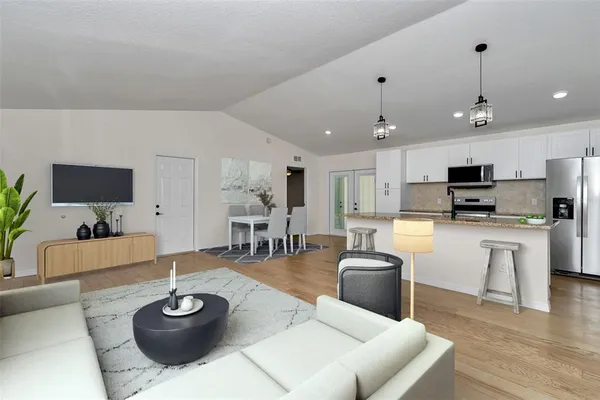 a living room with furniture a flat screen tv and kitchen view
