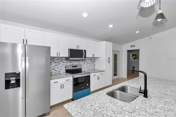 a kitchen with stainless steel appliances granite countertop a sink stove and refrigerator